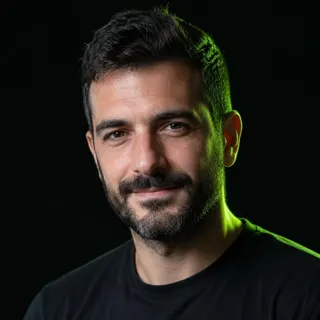 Πορτρέτο του Στέλιου Μαυρίδη, άντρα γύρω στα σαράντα με κοντά σκούρα μαλλιά και γκρι πουκάμισο