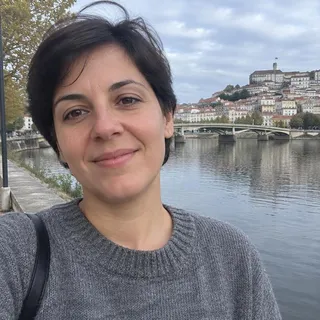 Retrato da Beatriz Alvernaz, uma mulher nos seus trinta anos com cabelo curto escuro e uma camisola cinzenta